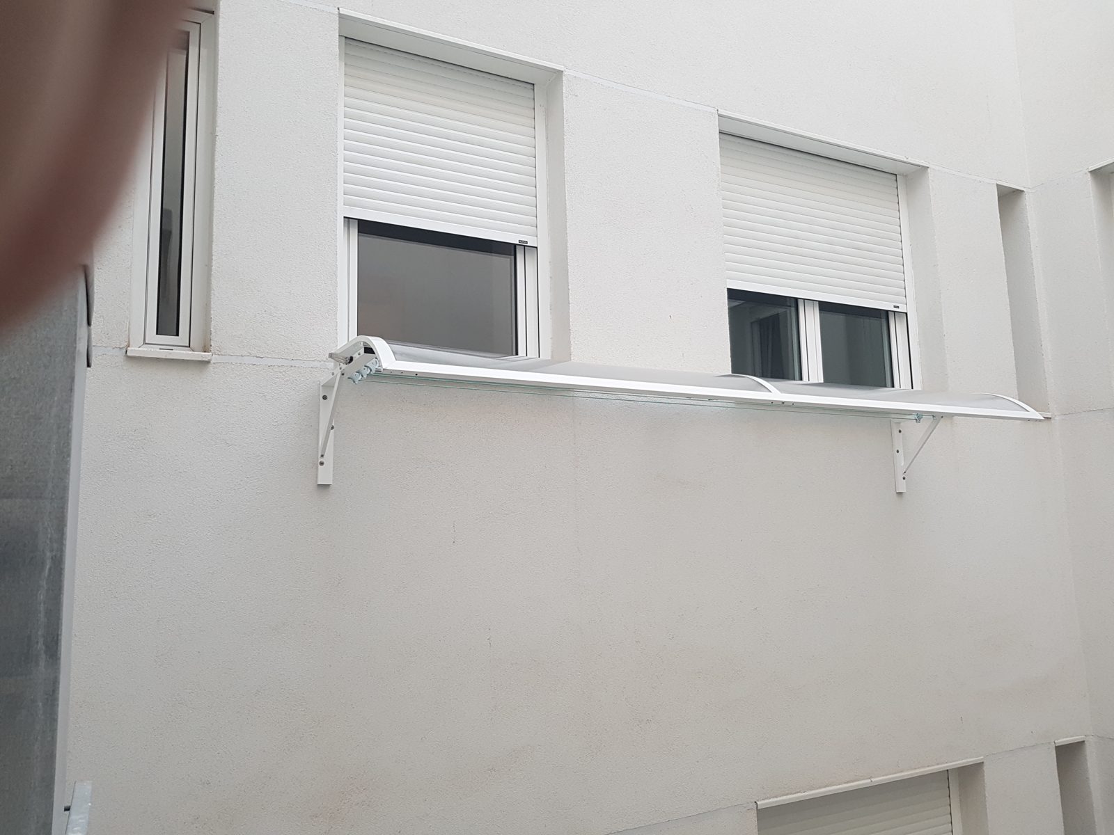 Tendal de exterior con marquesina de aluminio instalado por TuMampara en una fachada real