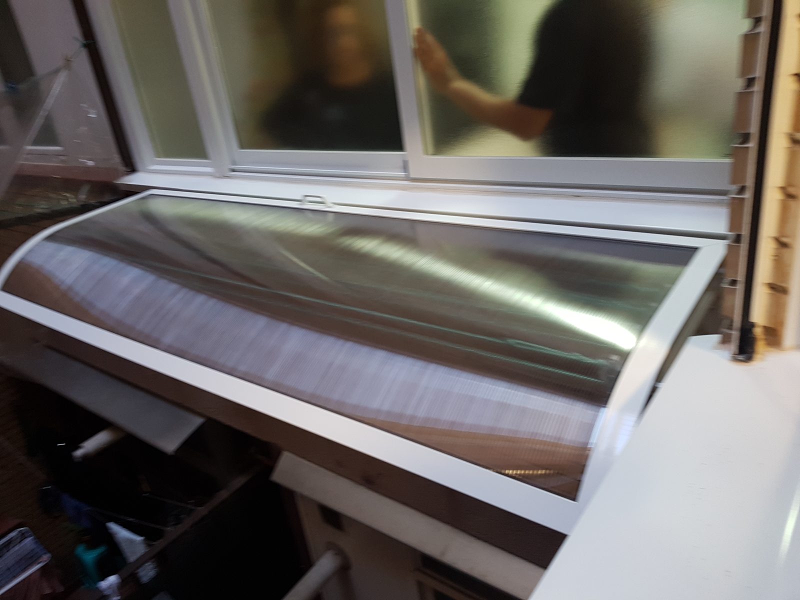 Tendal de exterior con marquesina y cuerdas instalado entre dos ventanas de una galería